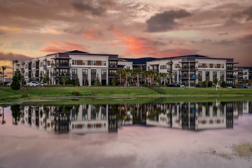 a view of an apartment building reflected in a lake at sunset