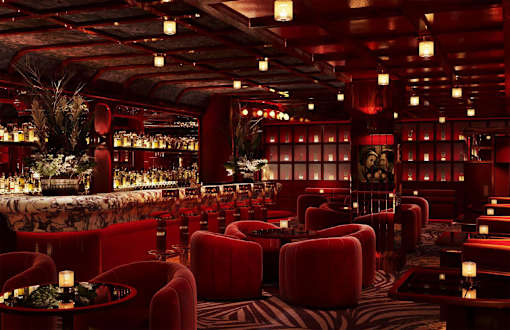 A dimly lit room with red chairs and tables.