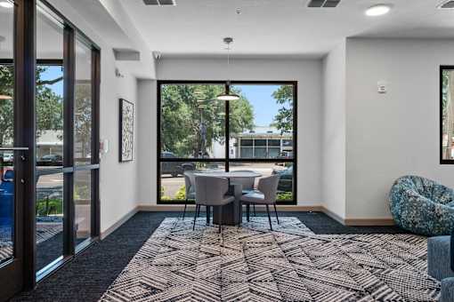 A room with a table and chairs with a view of a parking lot outside.