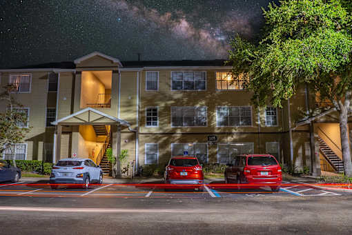 A building with a parking lot in front of it at night.