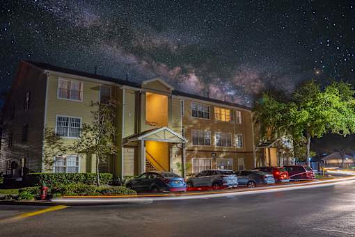 A building with a parking lot in front of it at night.