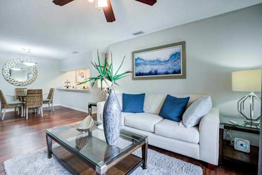 A living room with a white couch and a glass coffee table at Coral Club Apartments in Bradenton, FL