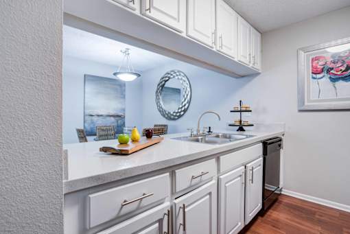 A kitchen with white cabinets and a wooden cutting board on the counter at Coral Club Apartments in Bradenton, FL