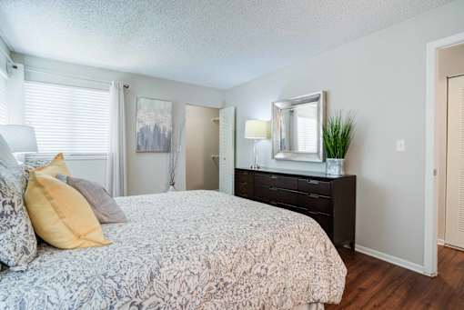 A bedroom with a bed, dresser, and mirror at Coral Club Apartments in Bradenton, FL