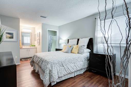 A bedroom with a large bed and a plant at Coral Club Apartments in Bradenton, FL