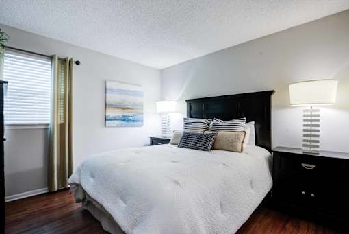 A bedroom with a large bed and a painting on the wall at Coral Club Apartments in Bradenton, FL