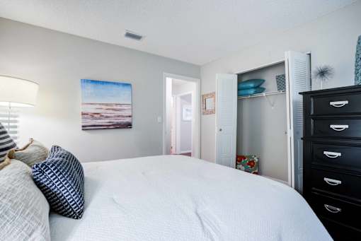 A bedroom with a large bed and a painting on the wall at Coral Club Apartments in Bradenton, FL