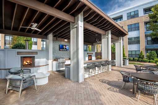 A patio with a fireplace and chairs.