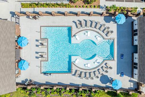 A large swimming pool surrounded by lounge chairs and umbrellas.