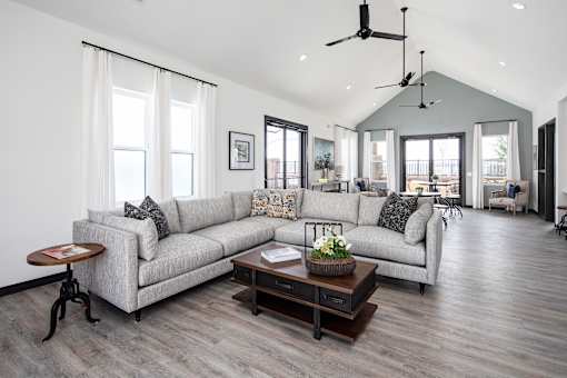 A living room with a grey couch, a coffee table, and a ceiling fan.