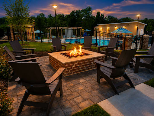 A fire pit in the middle of a patio surrounded by chairs.
