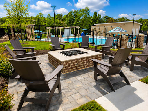 A patio with a fire pit and chairs.