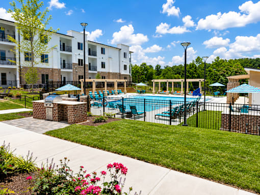 A pool surrounded by a black fence and a building in the background.