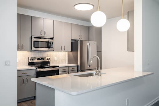A modern kitchen with a white countertop and stainless steel appliances.