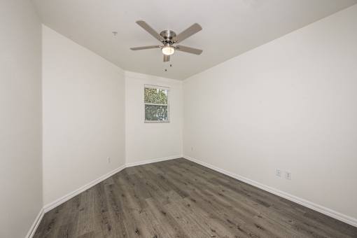 A room with a ceiling fan and wooden flooring.