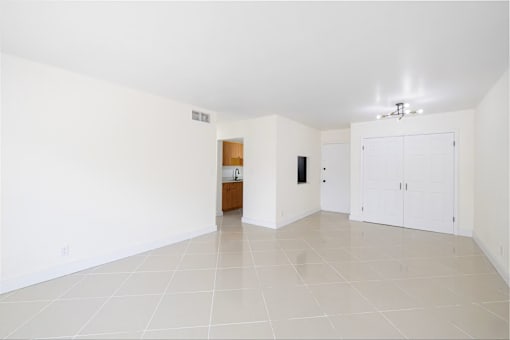 A spacious room with white walls and a tiled floor.