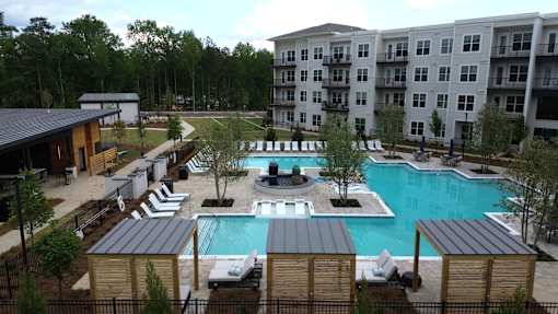A large swimming pool surrounded by lounge chairs and trees.