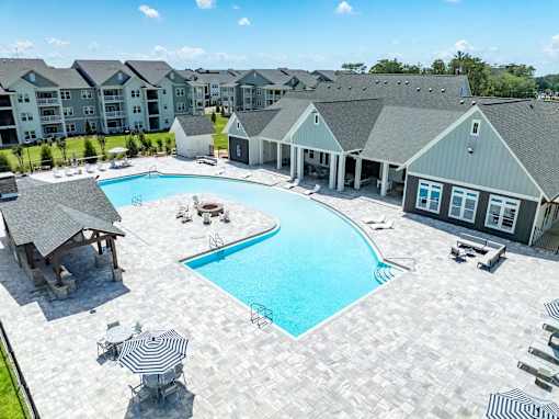 A large swimming pool surrounded by a patio and a building in the background.