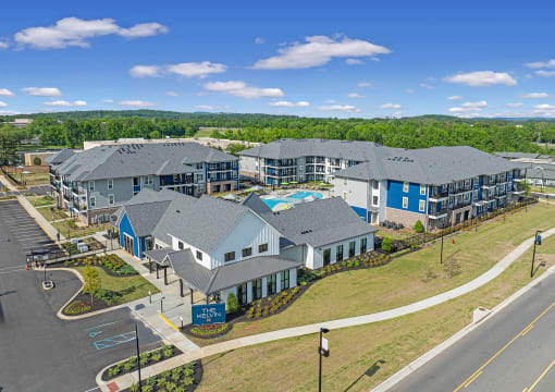 Huntsville, AL Luxury Apartments - The Kelvin - Aerial View of Property Exterior with White and Blue Walls, Grey Roofing, View of Pool, Surrounding Street, and Trees