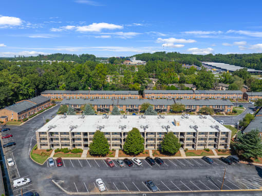 an aerial view of a large building with a parking lot and trees