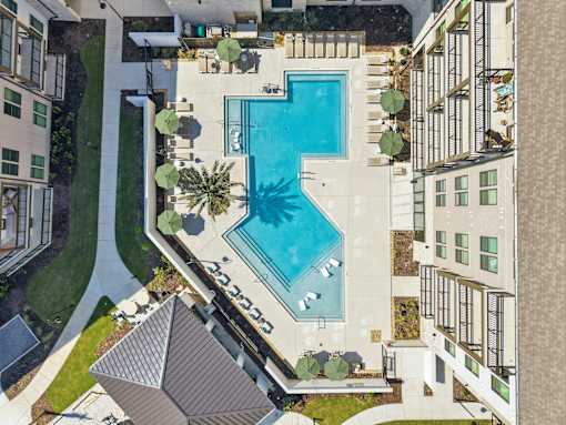 Heated swimming pool surrounded by a concrete patio and a white fence.
