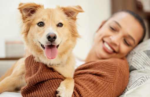 A man is holding a happy dog in his arms.