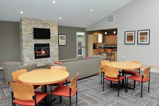 A stone fireplace is in the corner of a room with a table and chairs.