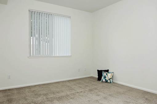A room with a window and a pillow on the floor.