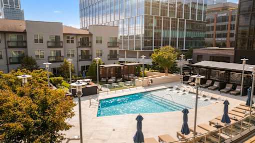 A swimming pool surrounded by a patio with chairs and umbrellas.