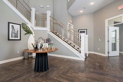 A foyer with a staircase and a table with a vase of flowers on it.