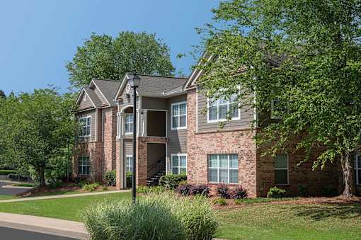 A large brick house with a tree in front.