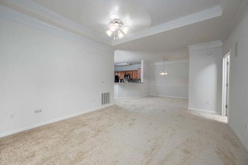 A large, empty room with a carpeted floor and a ceiling fan.