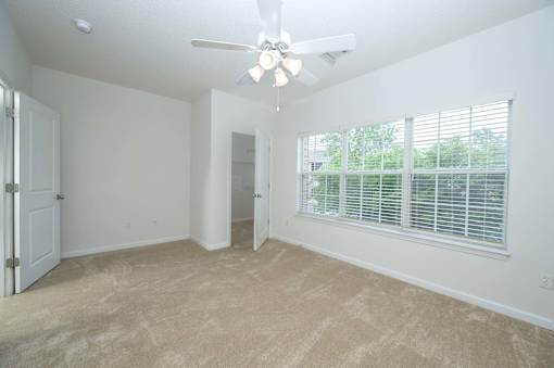 A room with a ceiling fan and a window with blinds.