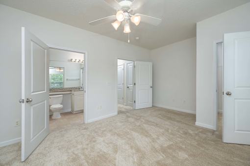 A spacious room with a ceiling fan and carpeted floor.