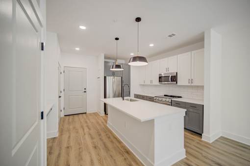 A kitchen with a white island and wooden floors.