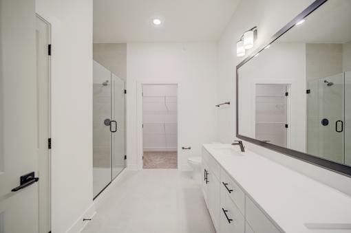A white bathroom with a large mirror and a walk-in shower.