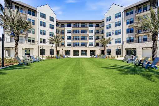 A large grassy area in front of a white building with palm trees.