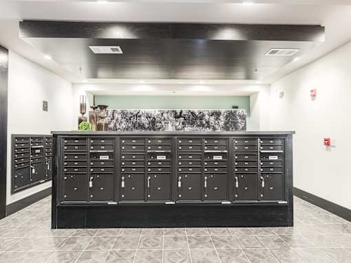 A black mailbox with a green wall in the background.