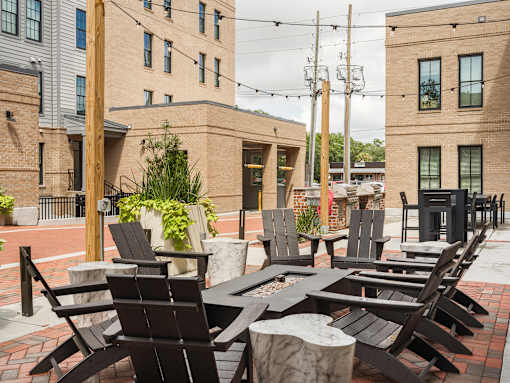 A row of black chairs are lined up on a brick patio.
