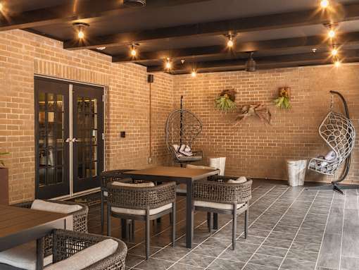 A room with a brick wall and a hanging chair.