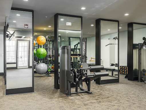 A gym with a variety of equipment including a squat rack, bench, and exercise balls.