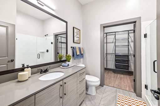 A bathroom with a toilet, sink, and mirror.