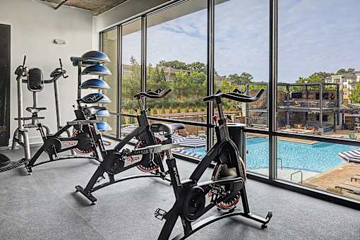 A gym with exercise bikes and a view of a pool.