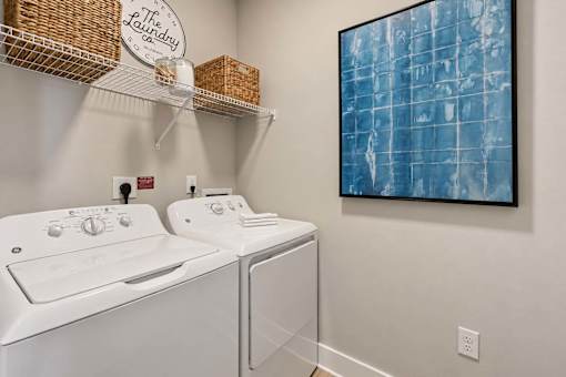 A laundry room with a washer and dryer and a painting on the wall.