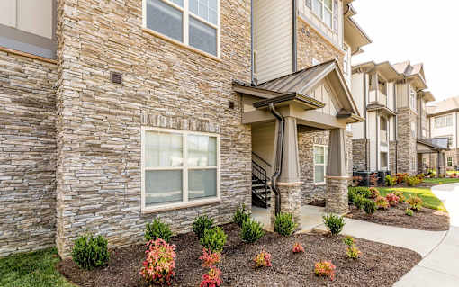 a view of the exterior of an apartment building with a sidewalk in front of it