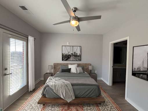 A bedroom with a bed, a ceiling fan, and a rug.