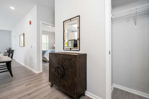 A brown wooden chest of drawers with a mirror on top is in a room with white walls.