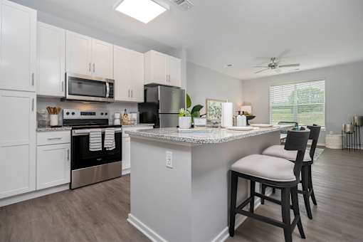 A kitchen with a white island and black bar stools.