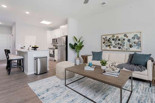 A modern living room with a kitchen in the background.
