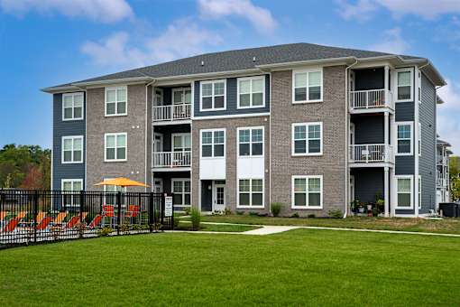A large grey apartment building with a black fence in front.